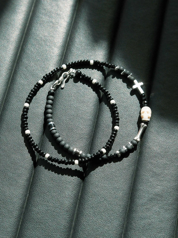 Dark aesthetic men’s bracelet with black beads, silver cross and skull in cinematic lighting