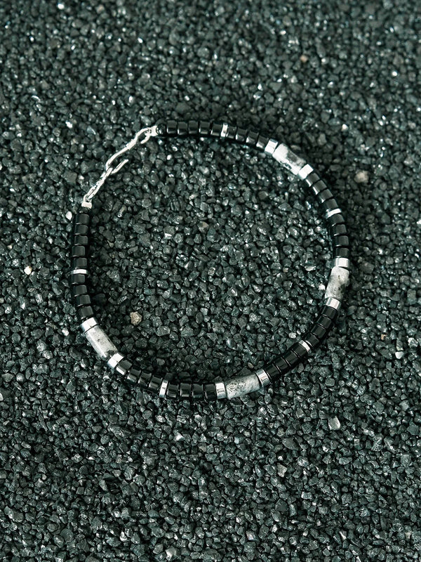Men’s obsidian bracelet on dark stone texture, black beaded bracelet with silver and grey stone accents