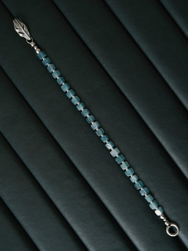 Artistic display of a men’s blue jade bracelet with sterling silver feather clasp, modern jewelry with quiet luxury appeal