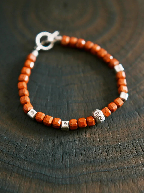 Editorial product display of a handcrafted red agate and sterling silver men’s bracelet with refined visual contrast