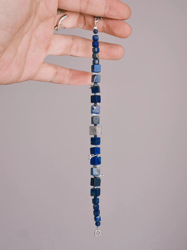 Hand holding lapis lazuli cube bead bracelet with sterling silver accents for men