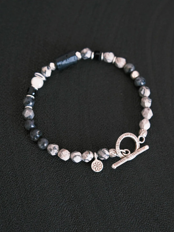 Artistic product layout of handmade men’s gemstone bracelet on textured dark surface