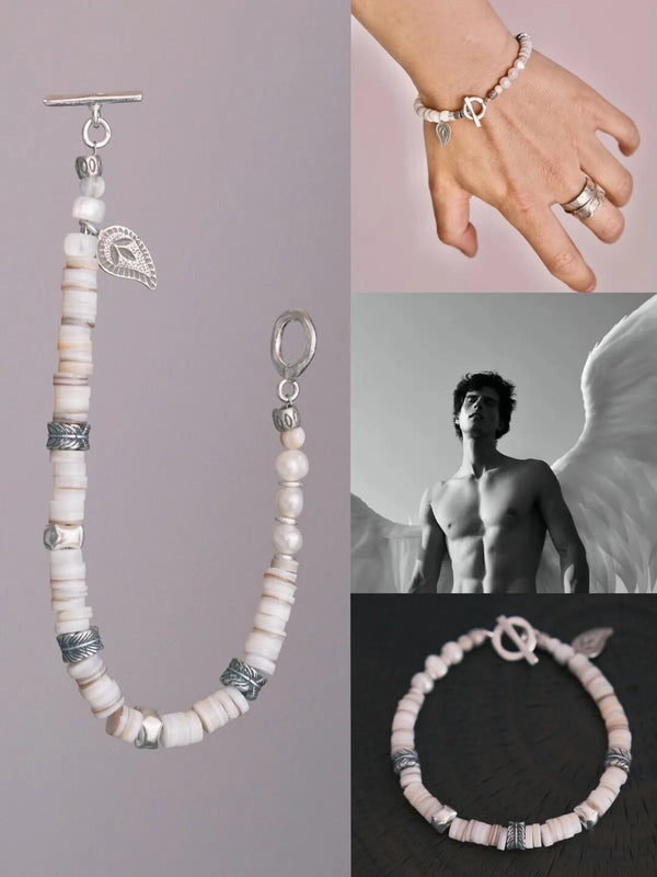 Men’s white shell pearl bracelet laid flat with silver feather charm and toggle clasp, clean jewelry aesthetic