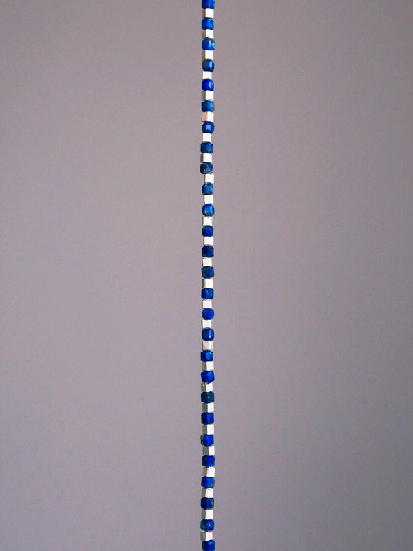 Close-up of natural lapis lazuli beads and sterling silver blocks, blue gemstone bracelet for men, refined minimal design.