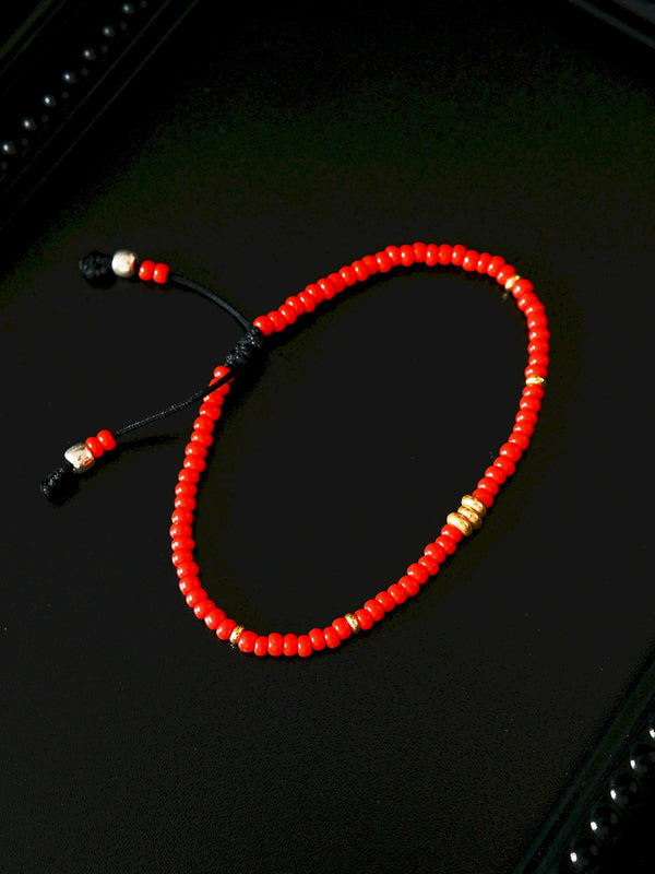 Red Signal bracelet on black display tray, red colored-glaze beads with gold accents, quiet masculine jewelry aesthetic