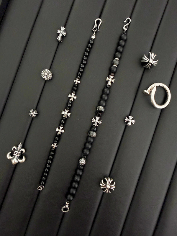 Close-up of matte black onyx beads, grey stone accents, and silver cross details on a men’s bracelet.