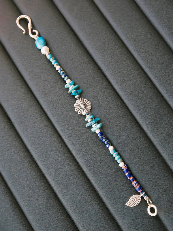 Close-up detail of turquoise beads, pearl, silver flower charm, and Miyuki colored-glaze on Mineral Soul Series Stone Bloom men’s bracelet.
