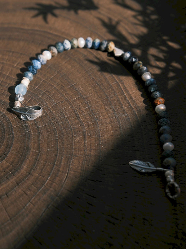 Men’s Free Wing bracelet styled in a minimal work setting, sunset stone and silver feather jewelry for focused modern daily wear.