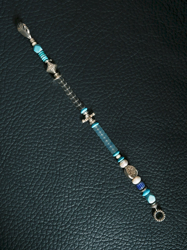 Close-up detail of turquoise, aquamarine, clear quartz, pearl, and silver feather elements on a men’s beaded bracelet, refined natural gemstone aesthetic.