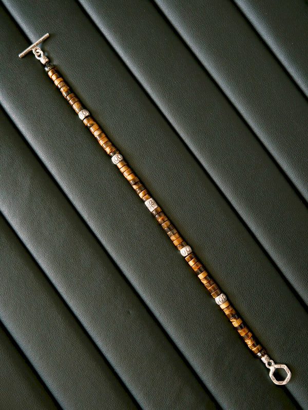 Close-up detail of natural tiger eye beads and hand-hammered silver elements, minimal men’s bracelet with warm brown maillard tones.