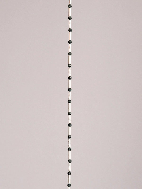 Close-up detail of 8A 36-facet black spinel beads and 925 sterling silver tube elements in a slim men’s bracelet.