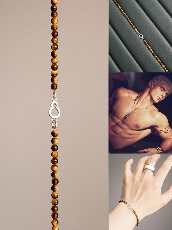 Flat lay of men’s tiger eye and sterling silver bracelet from Mineral Soul Series, featuring a FuLu gourd charm on dark leather texture with refined minimal style.