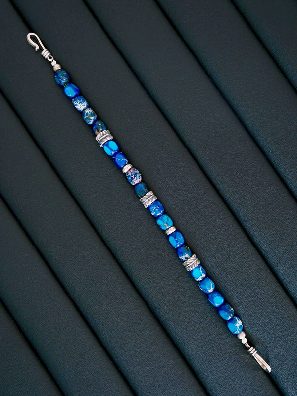Moody black and blue men’s bracelet styling with Ocean Wing blue stone beads, sterling silver details, and restrained masculine energy.