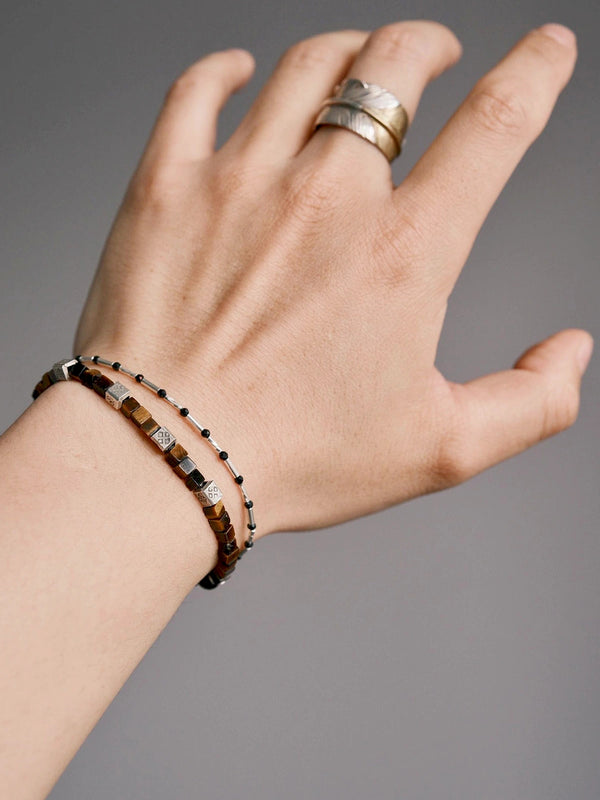 Men’s tiger eye bracelet stacked with a slim beaded bracelet, showing Maillard tones, silver accents, and quiet luxury styling.