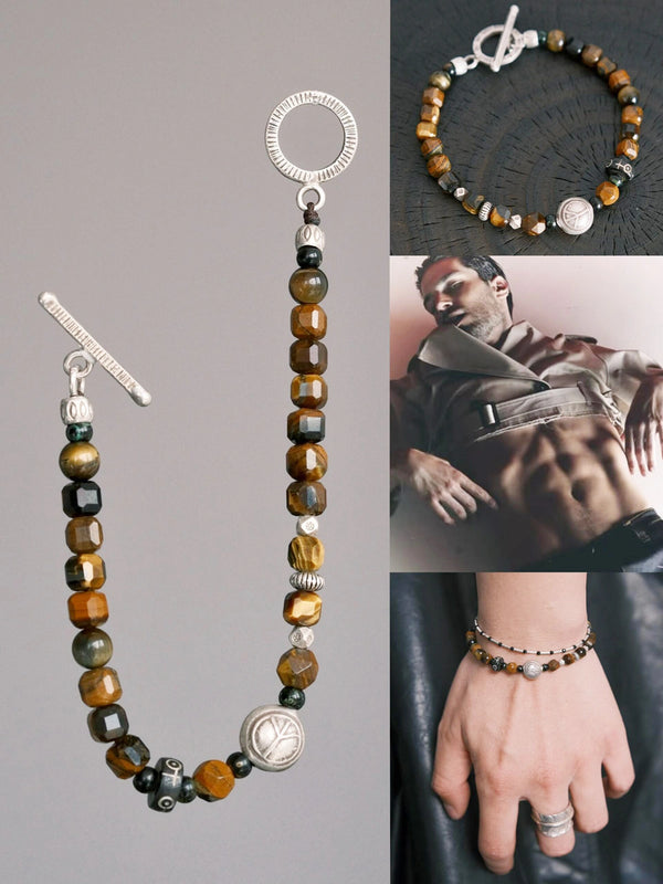 Tiger eye and horn bead men’s bracelet laid flat on a dark textured surface, showing silver toggle clasp and maillard brown tones.