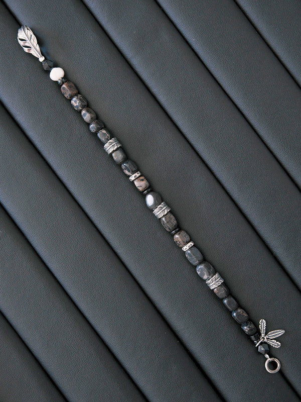 Black and white masculine mood image with dark wing-inspired jewelry styling, expressing quiet control, urban restraint, and refined male presence.