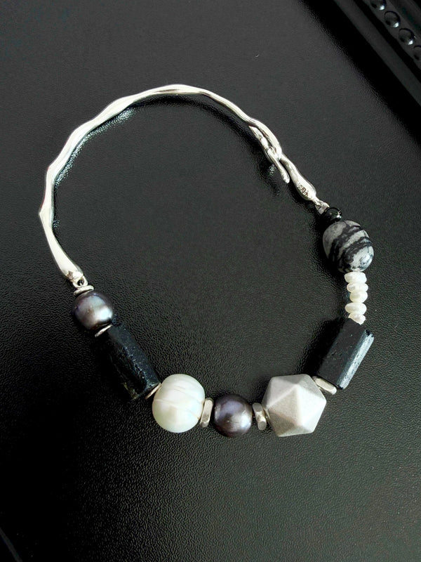 Men’s pearl and black tourmaline bracelet on dark background, featuring silver Mobius ring and refined masculine jewelry styling.