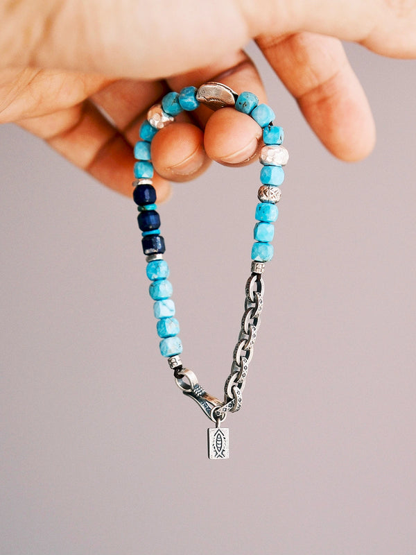 Hand holding men’s Blue Voyager bracelet with turquoise beads, lapis lazuli accents, and hammered S925 silver details.