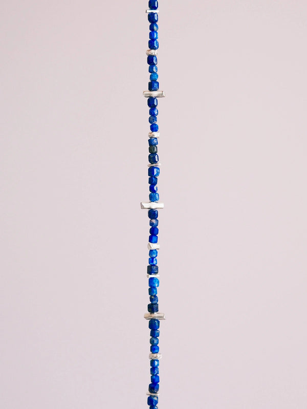 Close-up of lapis lazuli beads and hammered silver accents, natural stone texture, refined blue bracelet for men.