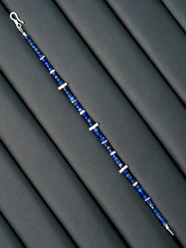 Moody blue-toned men’s jewelry image with lapis lazuli bracelet, quiet confidence mood, minimal masculine aesthetic.