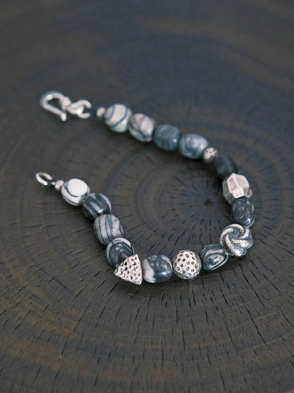 Close-up of black and white webbed jasper-style stone beads and textured sterling silver meteor-inspired accents on men’s bracelet.