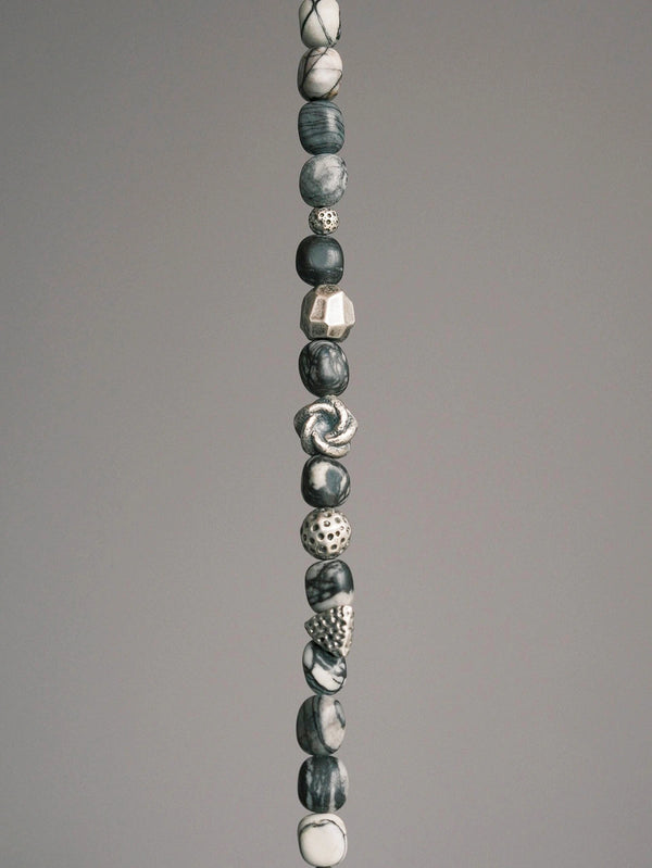 Close-up of black and white webbed jasper-style stone beads and textured sterling silver meteor-inspired accents on men’s bracelet.