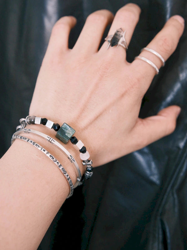 Stacked men’s bracelets with Urban Stoic Series Dark Monolith, silver bangles, black obsidian beads, and dark minimal jewelry style.