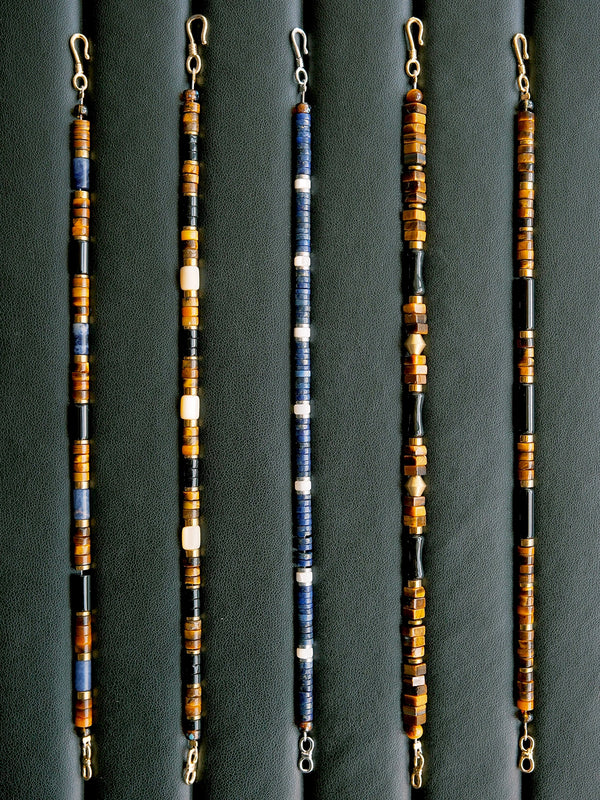 Men’s lapis lazuli and mother-of-pearl bracelet on dark background, showing refined blue tones, platinum-tone details, and quiet luxury styling.