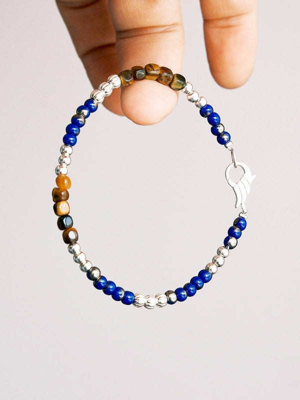 Hand holding Identity Series Silver Epoch men’s bracelet, tiger eye square beads, sterling silver spacers, blue colored-glaze accents.