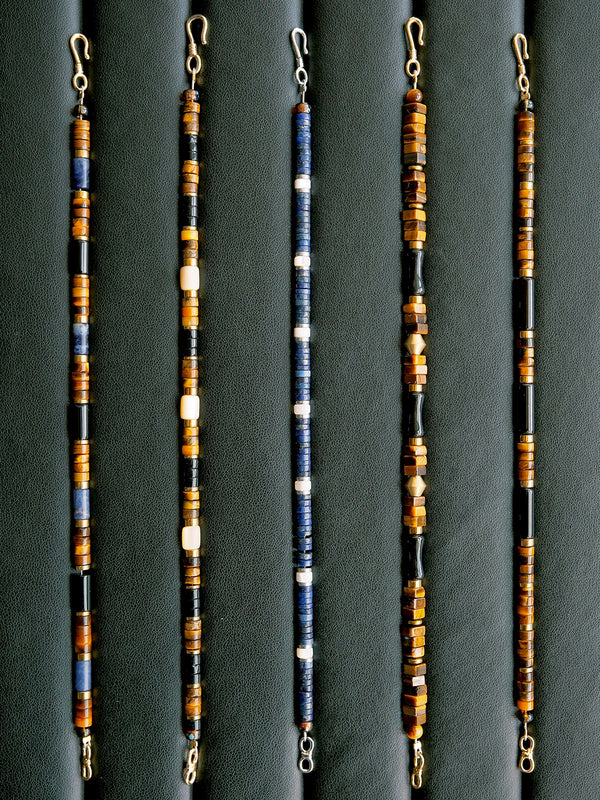 Men’s blue and brown beaded bracelet laid flat on dark leather, tiger eye, K2 blue stone and hematite, urban stoic style.