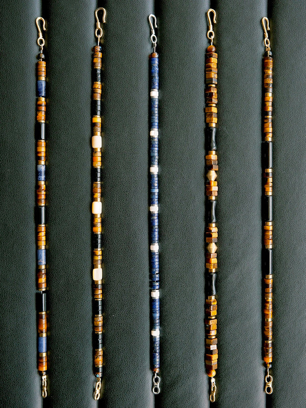 Men’s blue and brown beaded bracelet laid flat on dark leather, tiger eye, K2 blue stone and hematite, urban stoic style.