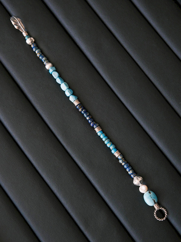 Blue Plume men’s bracelet mood image with turquoise tones, silver feather symbol, and quiet masculine energy for refined daily wear.