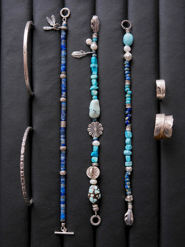 Men’s turquoise and silver bracelet flat lay on dark wood, Mineral Soul Series Blue Plume, refined beaded bracelet with pearl and silver feather accent.