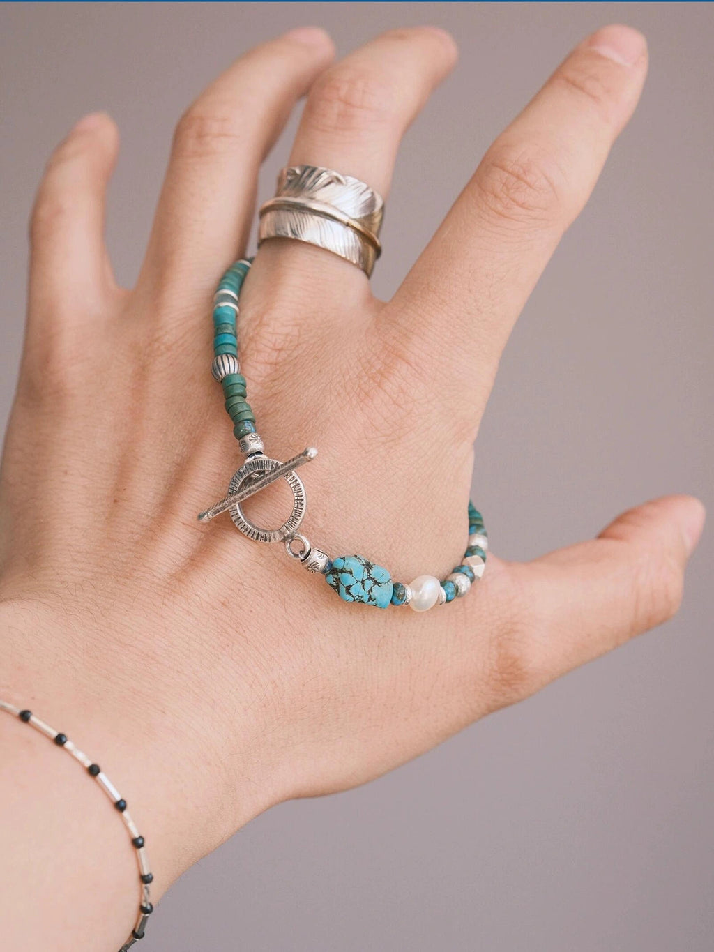 Hand holding Mineral Soul Series Mountain Tide bracelet, turquoise beads, baroque pearl and silver details in close-up view