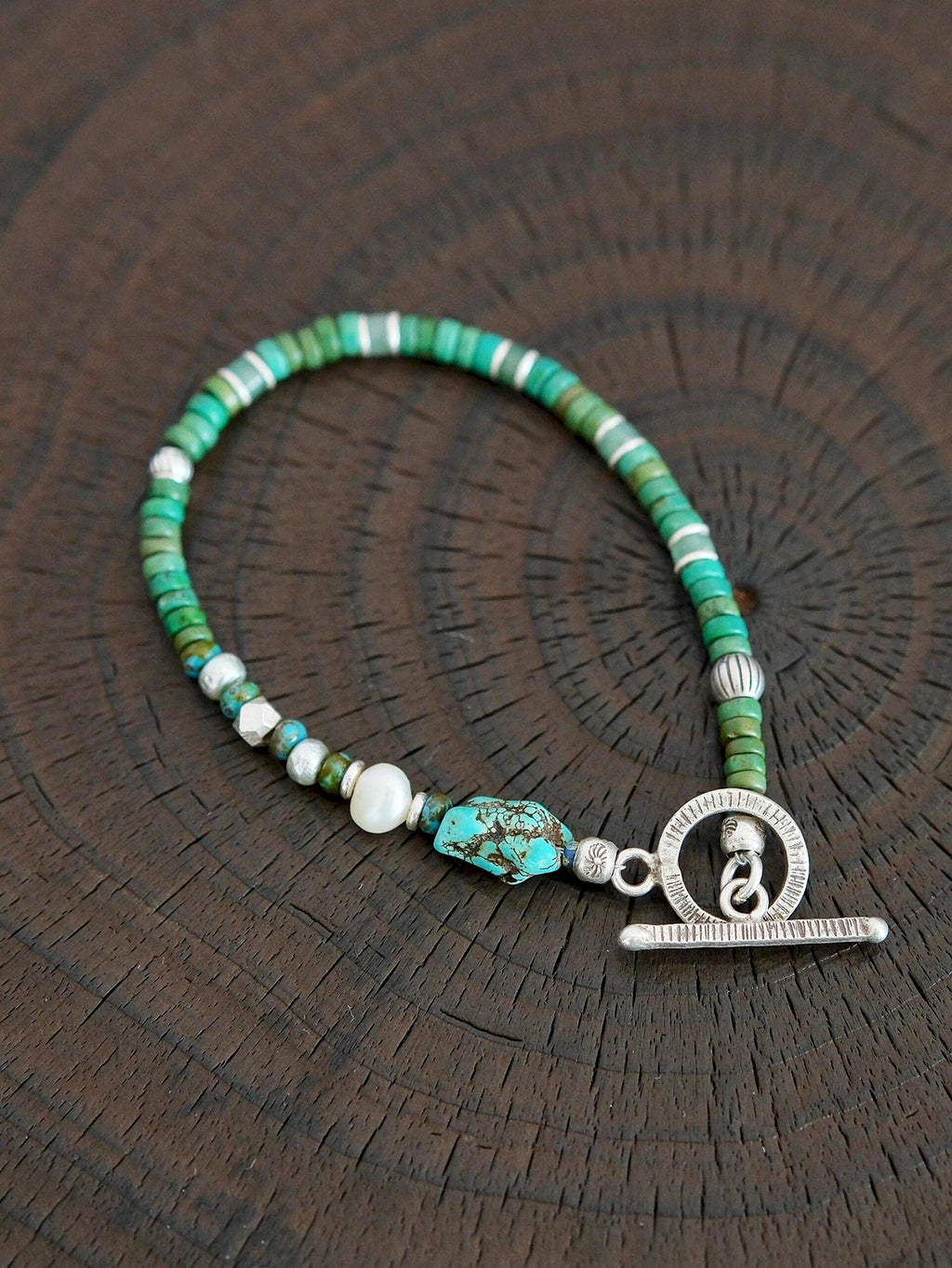 Flat lay of men’s turquoise, aventurine and pearl bracelet with hammered silver toggle clasp, natural mineral style
