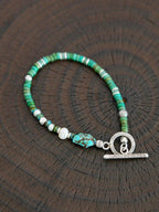 Flat lay of men’s turquoise, aventurine and pearl bracelet with hammered silver toggle clasp, natural mineral style