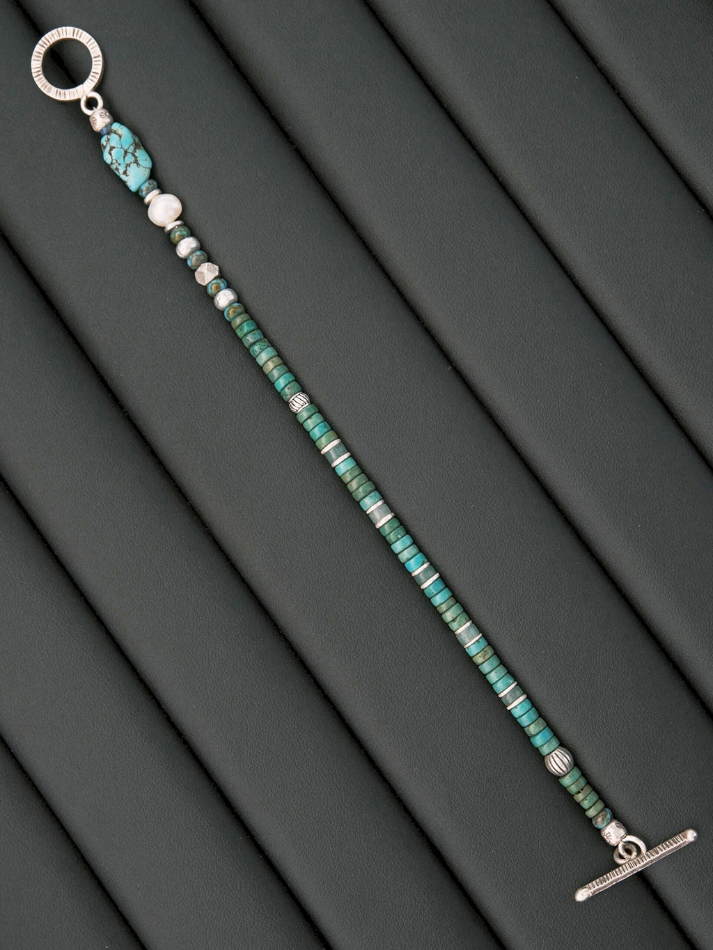 Moody men’s bracelet detail with turquoise and silver contrast, grounded masculine jewelry aesthetic