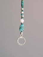 Close-up detail of turquoise, aventurine, Miyuki colored-glaze, baroque pearl and hammered silver beads on men’s bracelet