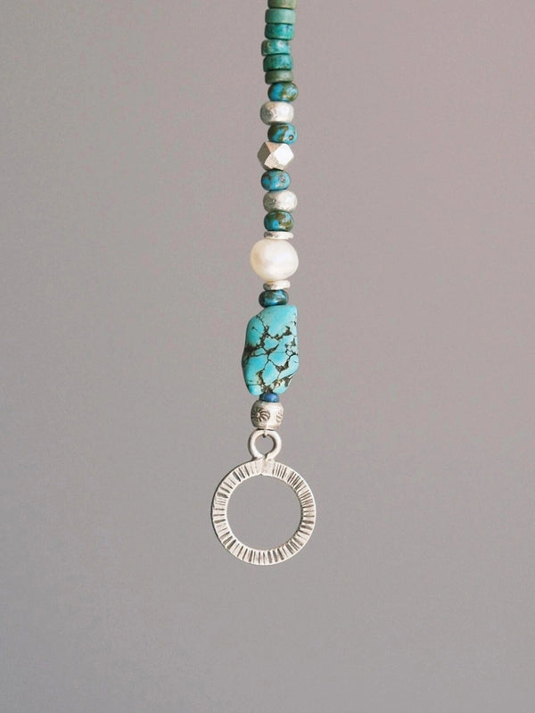 Close-up detail of turquoise, aventurine, Miyuki colored-glaze, baroque pearl and hammered silver beads on men’s bracelet
