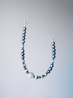 Black and white mood image of a men’s pearl silver bracelet, quiet confidence, stoic jewelry aesthetic.