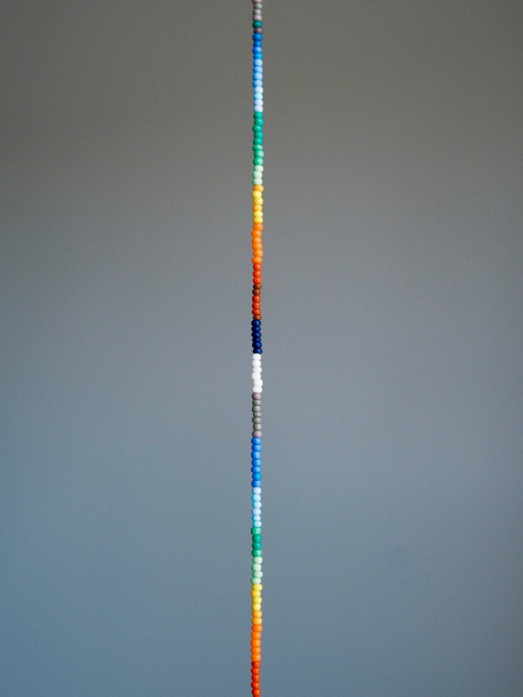 Straight layout of thin rainbow colored-glaze bracelet, sterling silver clasp, modern men’s beaded bracelet design
