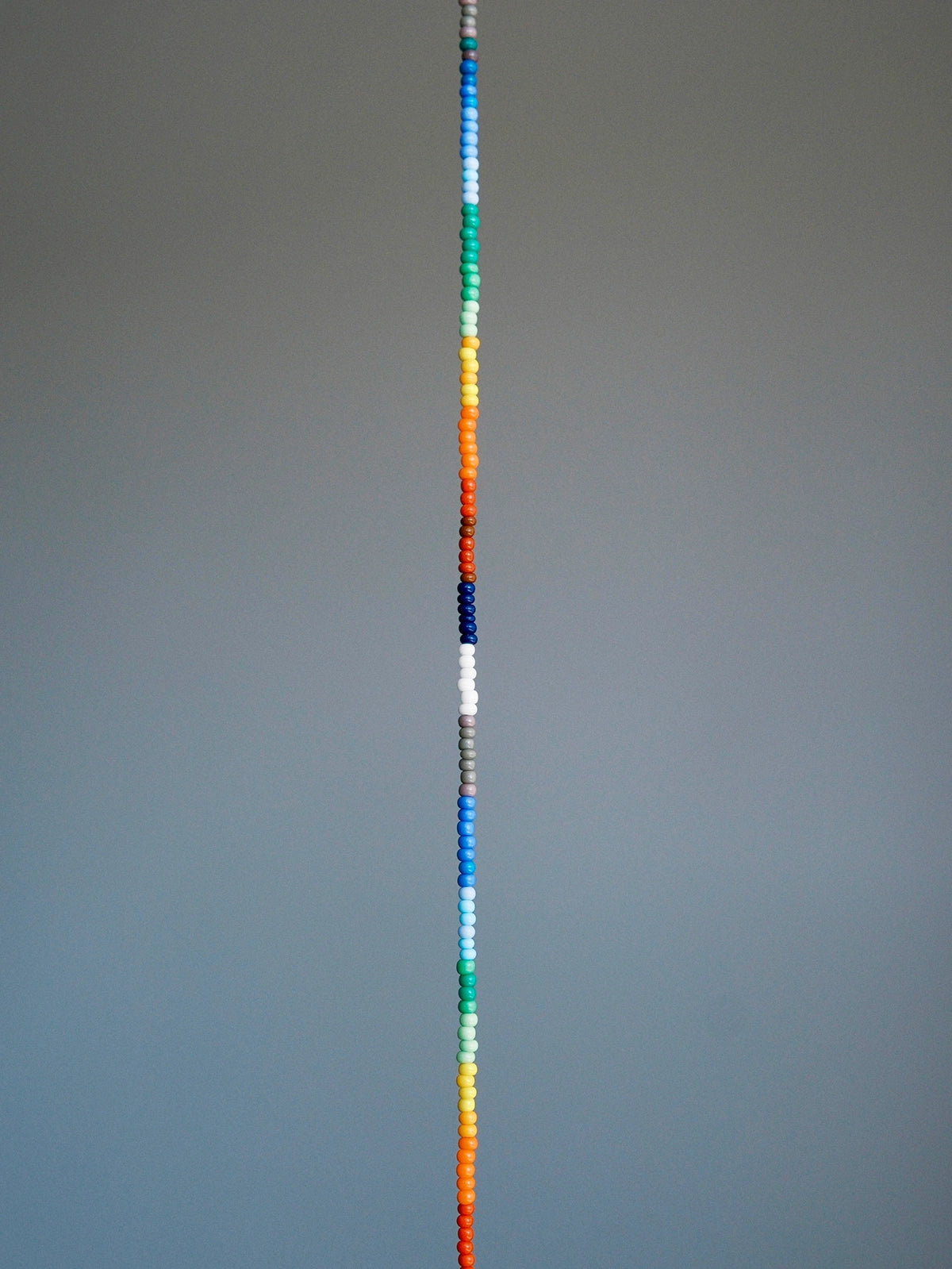 Straight layout of thin rainbow colored-glaze bracelet, sterling silver clasp, modern men’s beaded bracelet design