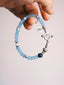 Hand holding Mineral Soul Series Blue Shoal bracelet with blue chalcedony beads, lapis lazuli accent and sterling silver toggle clasp