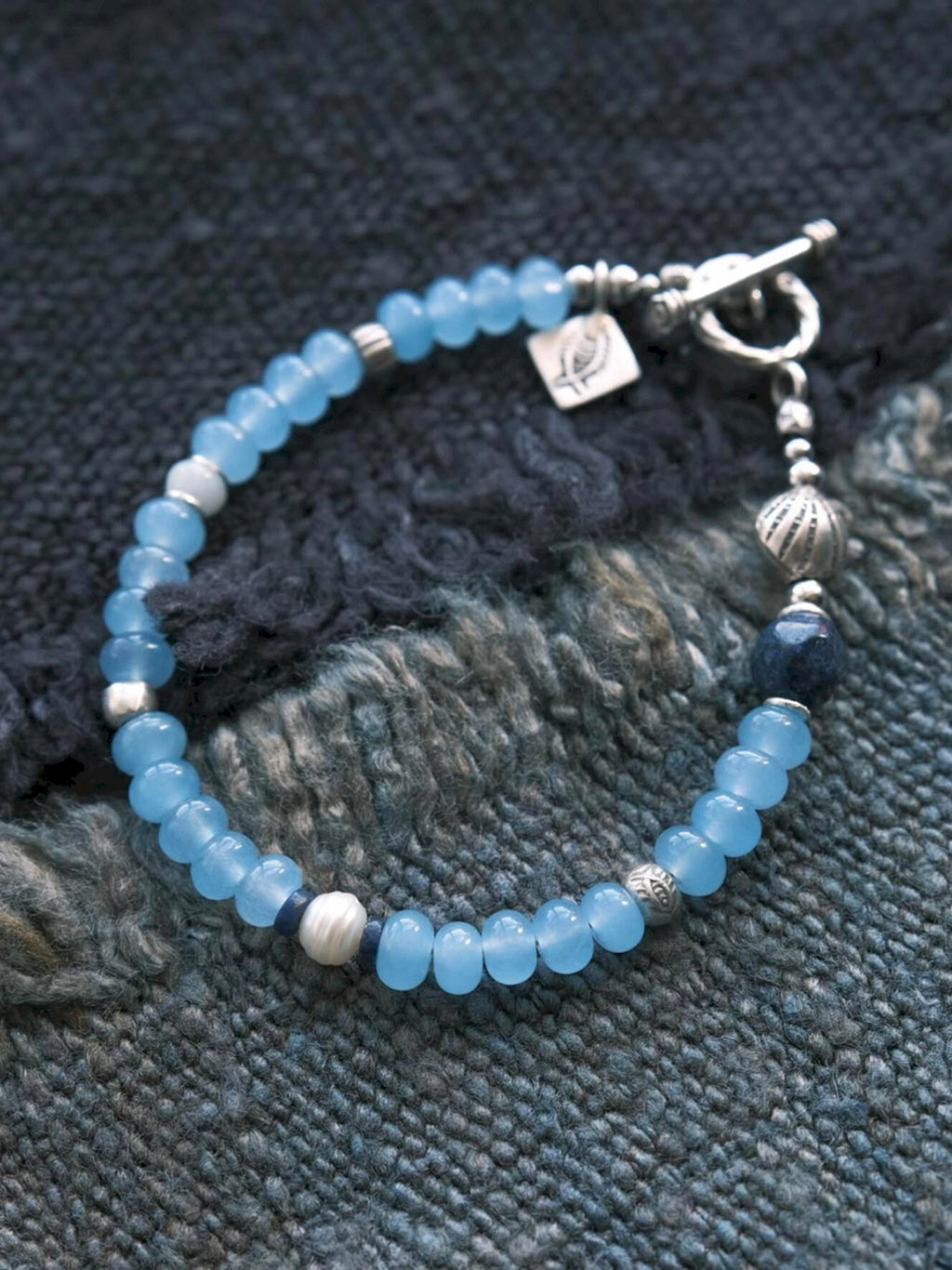 Close-up of blue chalcedony beads, natural pearl, lapis lazuli, jade accent and sterling silver details on Blue Shoal bracelet