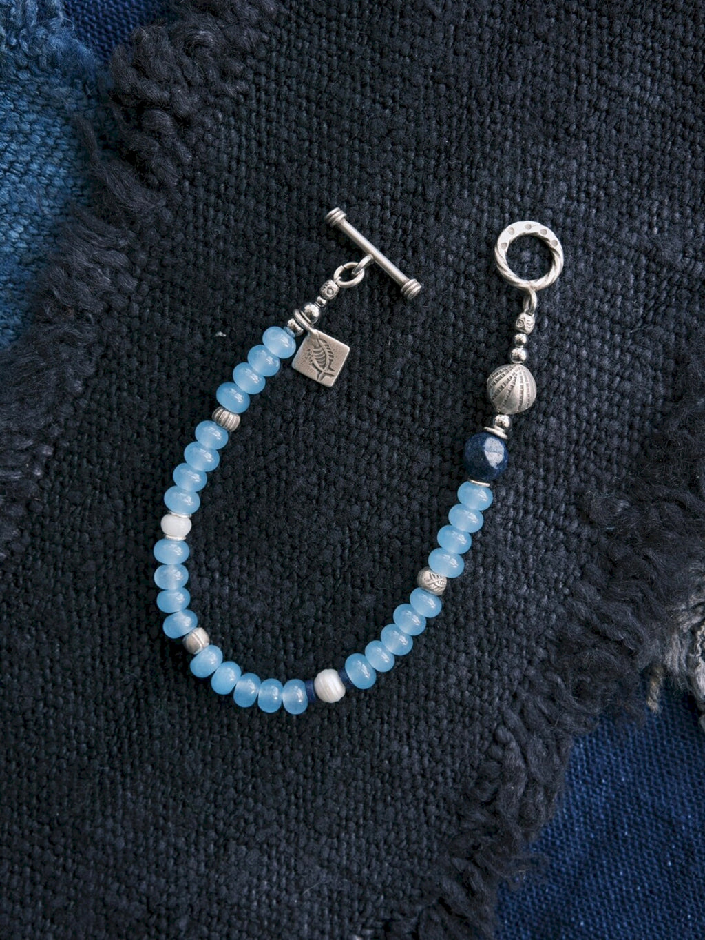 Close-up of blue chalcedony beads, natural pearl, lapis lazuli, jade accent and sterling silver details on Blue Shoal bracelet