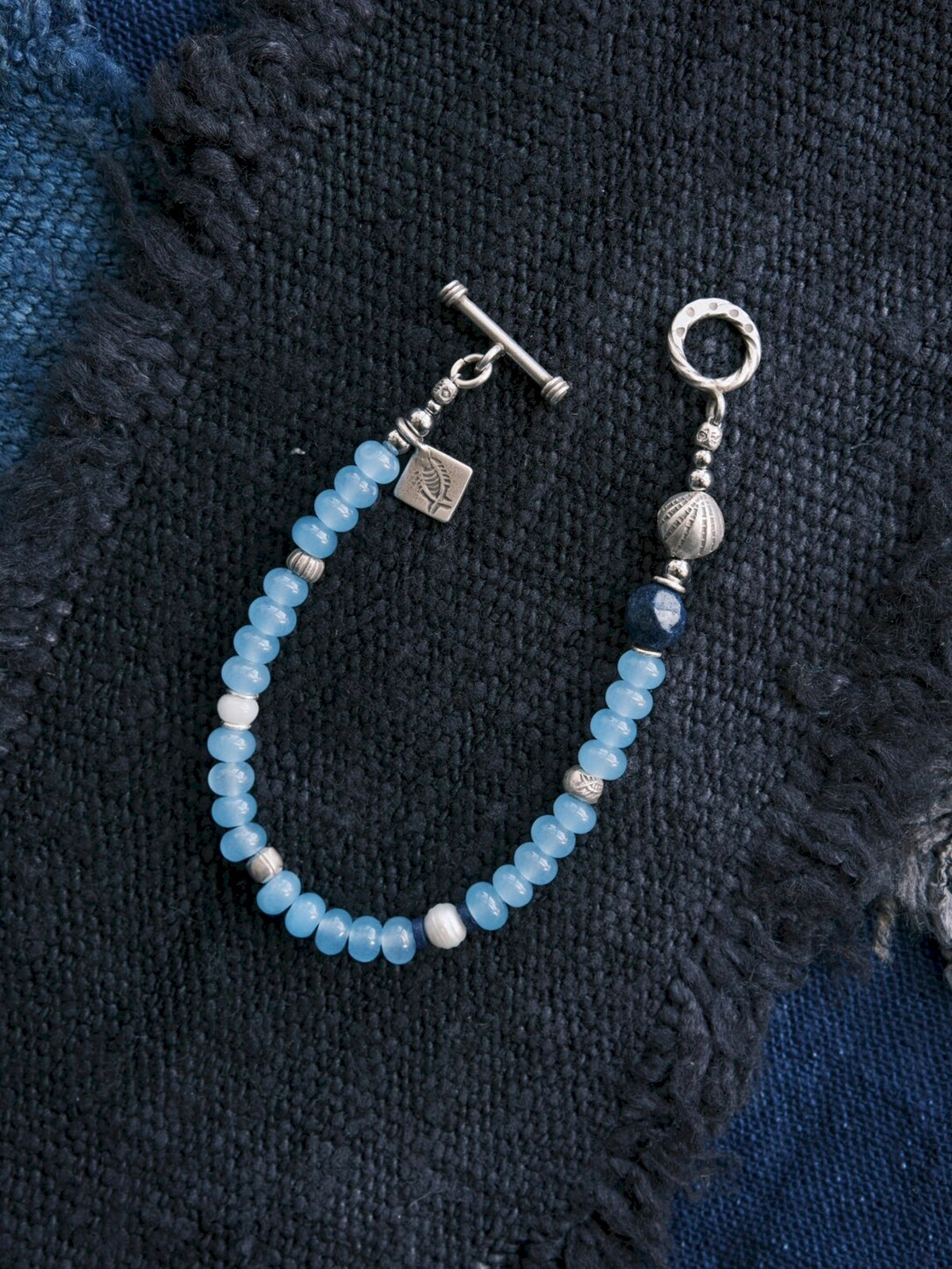 Close-up of blue chalcedony beads, natural pearl, lapis lazuli, jade accent and sterling silver details on Blue Shoal bracelet