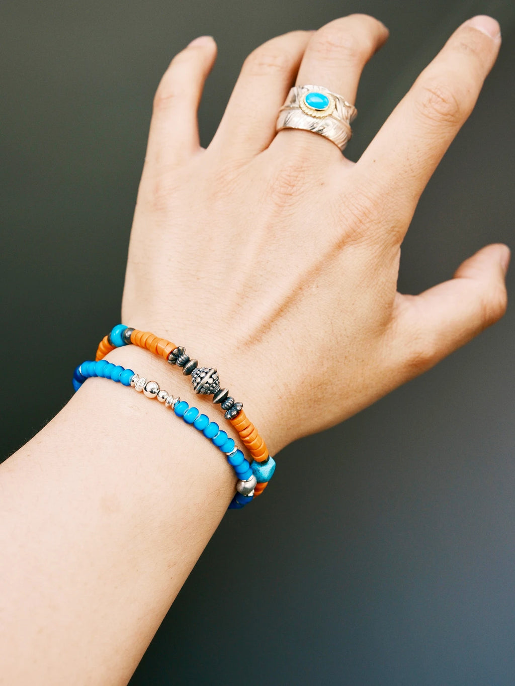 Men wearing Sunset Nomad turquoise bracelet on wrist, stacked with silver bangle and turquoise ring, vintage western jewelry style.