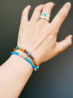 Men wearing Sunset Nomad turquoise bracelet on wrist, stacked with silver bangle and turquoise ring, vintage western jewelry style.