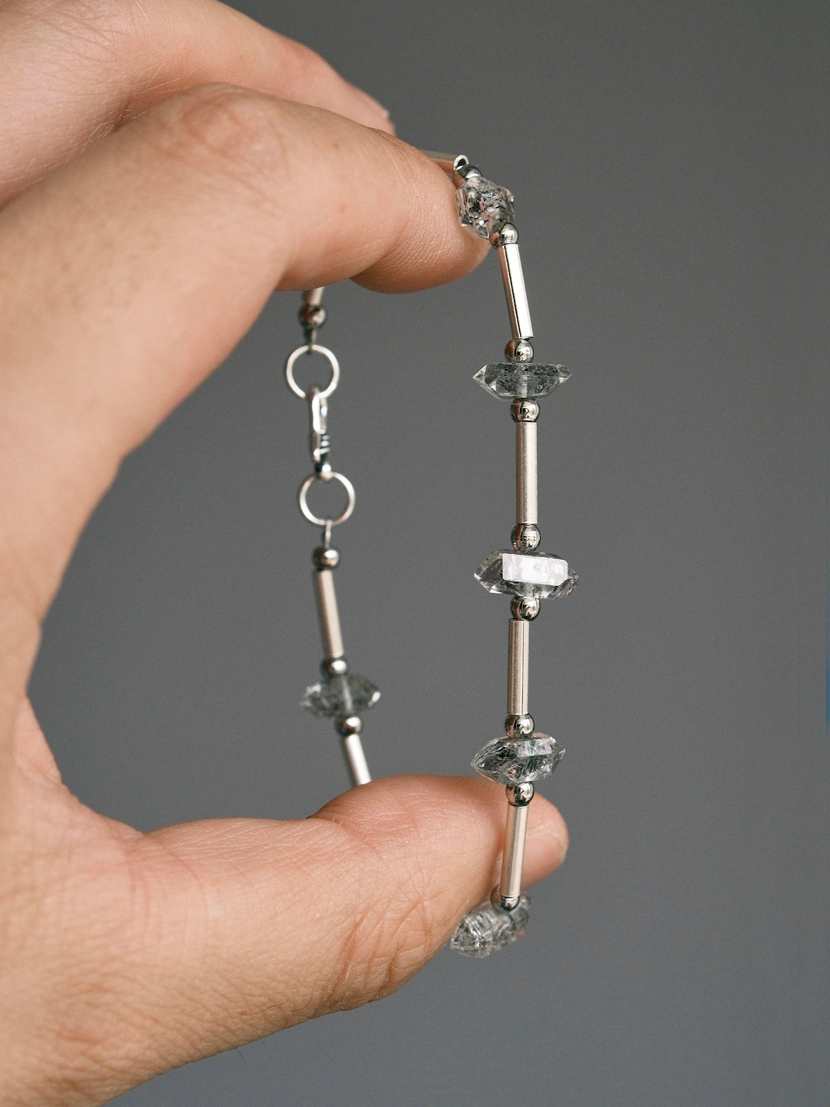 Handheld men’s Herkimer quartz bracelet showing raw crystal texture, silver tube details, and minimalist masculine style