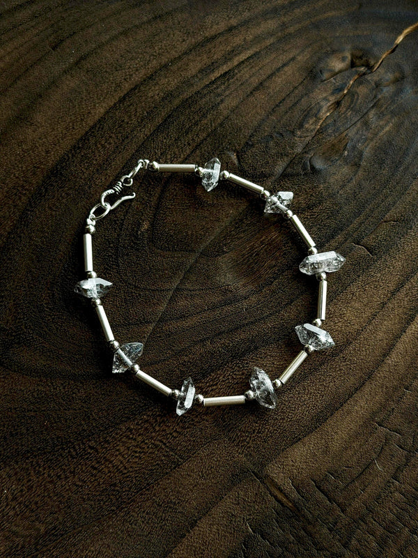 Sterling silver and flash quartz bracelet on dark wood, masculine crystal jewelry with grounded natural contrast